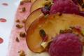 Tartines pêches-framboises parsemées de pistaches et de miel sur de la crème aux amandes