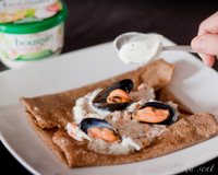 Les classiques moules marinières sont crémées avec du Boursin cuisine ail et fines herbes et sont servies sur la traditionnelle galette de blé noir.