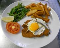 Blancs de dinde panés à l'anglaise surmontés d'un œuf frit et d'anchois frais.