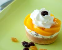Un fond de pâte sablée garni de Crème Glacée Carte d"Or® Rhum Raisins surmonté d'une rosace de pêche au sirop et de crème Chantilly.