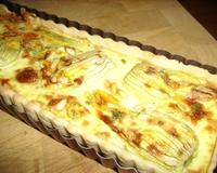 Je réalise la tarte sur un fond de pâte brisée. Elle est garnie de fleurs de courgette farcie à la ricotta et à la poudre d'amande.