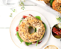 Bagel houmous, pousses d’épinards, tomates séchées et oignon rouge