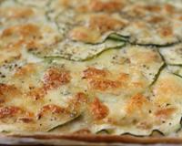 Une tarte aux fines rondelles de courgettes recouvertes de petits morceaux de comté, de mozzarella et d'herbes de Provence.
