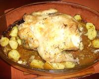 Poulet rôti au four cuit avec des pommes de terre, des oignons et de l'ail, sapoudré d'herbes de provence et badigeonné d'huile d'olive.