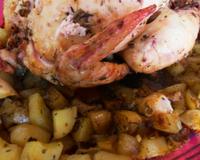Poulet rôti au four cuit avec des pommes de terre, des oignons et de l'ail, saupoudré d'herbes de provence et badigeonné d'huile d'olive.