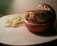 Un hamburger avec du pain complet, un steak maison de poulet, une sauce blanche à la ciboulette, des oignons rouges caramélisés, et une salade de fenouil !