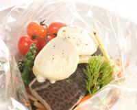 Dos de cabillaud cuit en papillote recouvert de lamelles de Chavignol mi- sec et servi sur une julienne de légumes d'automne légèrement craquante.