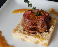 Un filet d'agneau farci à la compotée de fruits secs sur un lit de couscous aux raisins