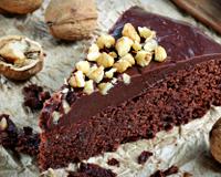 Un gâteau très chocolat avec des noix en poudre et recouvert d'un glaçage au chocolat.