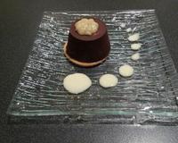 Mousse au chocolat au lait avec un cœur de banane enrobée d'une coque de chocolat noir sur un biscuit.