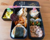 Un bento composé d'une aubergine farcie, d'un tartare de saumon, de chips de légumes, d'un onigiri au saumon, de légumes au wok, d'omelette japonaise, de billes de mozzarella…