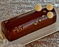Buche composée d'une bavaroise à la fève Tonka, avec un insert au cassis, déposée sur une dacquoise aux noix et couche croustillante avant d'être entièrement recouverte…