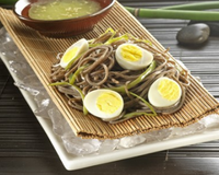 Salade de nouilles Soba garnie avec des oignons nouveaux, œufs de caille et pois gourmands accompagnée d'une sauce à l'huile de sésame, vinaigre de riz et wasabi.