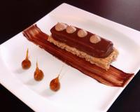 Dessert avec pour base une dacquoise fondante aux noisettes, surmontée d'un mousseux praliné et chablonné, ainsi que d'une crème fouettée légère au chocolat.
