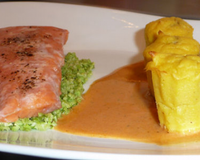 Un pavé de saumon cuit à 43°C, servi sur une semoule de chou fleur vert, accompagné de cannelés en pommes duchesses fourrés d'un pesto, et d'une sauce tomate.