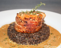 Un pavé de saumon enroulé de lard grillé et nappé d'une onctueuse sauce au vin blanc. Un plat terre et mer.