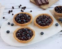 Des tartelettes originales à base de chocolat noir et myrtilles : une belle association et une recette par étapes, simple à reproduire à la…