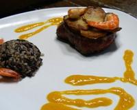 Un tournedos surmonté d'une rosace de pommes de terre et de crevettes une sauce aux fruits délicieuse.