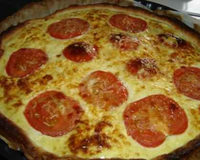 Une pâte recouverte de moutarde de gruyère râpé et de tomates coupées en tranches puis encore du gruyère rapé salé poivré un filet d'huile.