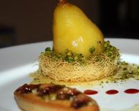 Une poire pochée au safran et aux épices dans un jus de pommes sur un nid de kadaïf (cheveux d'ange) le tout parsemé de pistaches, un dessert qui allie l'occident à l'orient.…