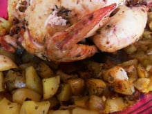 Poulet roti au four farci de pain à l'ail sur lit de pommes de terre