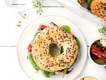 Bagel houmous, pousses d’épinards, tomates séchées et oignon rouge