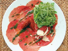 Salade de roquette sur carpaccio de bœuf au pesto, huile d'olive aux piments, et copeaux de parmesan