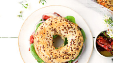 Bagel houmous, pousses d’épinards, tomates séchées et oignon rouge