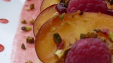 Tartines pêches-framboises parsemées de pistaches et de miel sur de la crème aux amandes