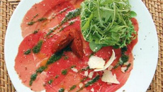 Salade de roquette sur carpaccio de bœuf au pesto, huile d'olive aux piments, et copeaux de parmesan