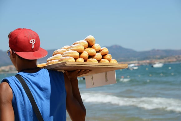 Vendeur de beignets à la plage. Adobestock