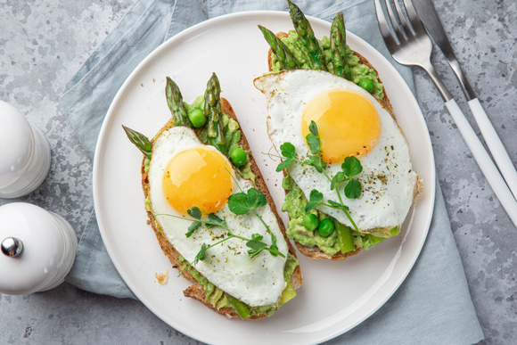 Tartines à l'avocat, asperges et œufs au plat. Adobestock