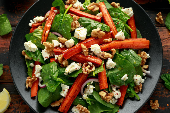 Salade de carottes rôties, pousses d'épinards, feta et noix. Adobestock