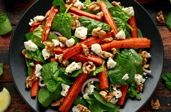 Salade de pousses d'épinards, carottes rôties, féta et noix. Adobestock