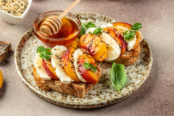 Fraîches et gourmandes, Cyril Lignac partage sa recette de tartines croustillantes à la burrata et aux pêches rôties !
