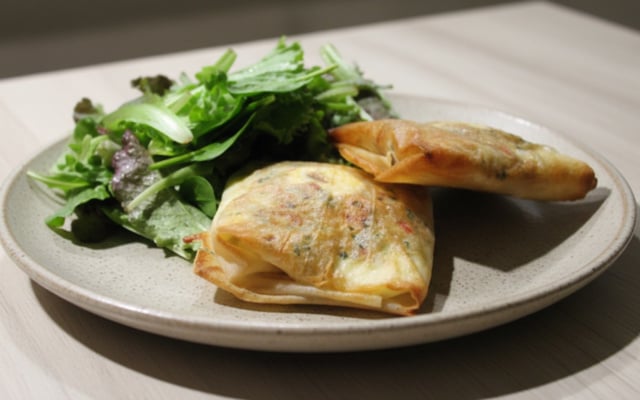 Brick à l'œuf avec oignons, fromage et herbes fraîches