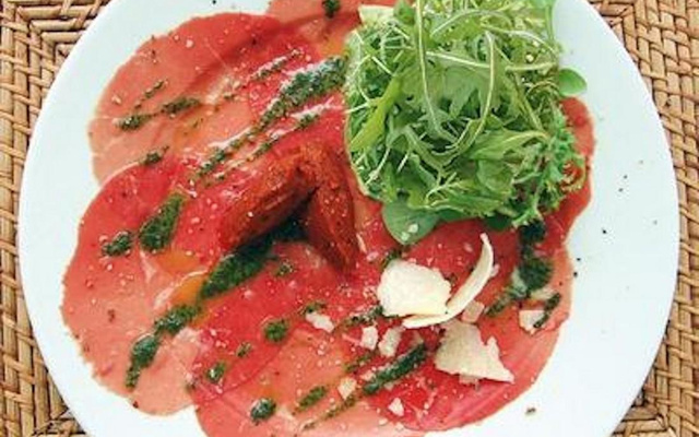 Salade de roquette sur carpaccio de bœuf au pesto, huile d'olive aux piments, et copeaux de parmesan