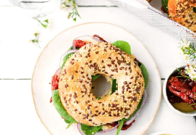 Bagel houmous, pousses d’épinards, tomates séchées et oignon rouge