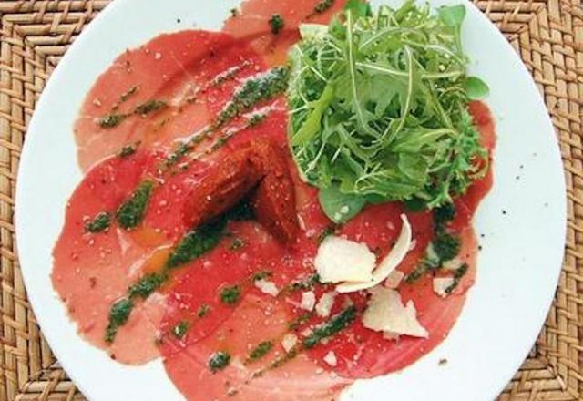 Salade de roquette sur carpaccio de bœuf au pesto, huile d'olive aux piments, et copeaux de parmesan